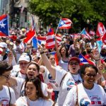 Group of people marching and waving Puerto Rican flags