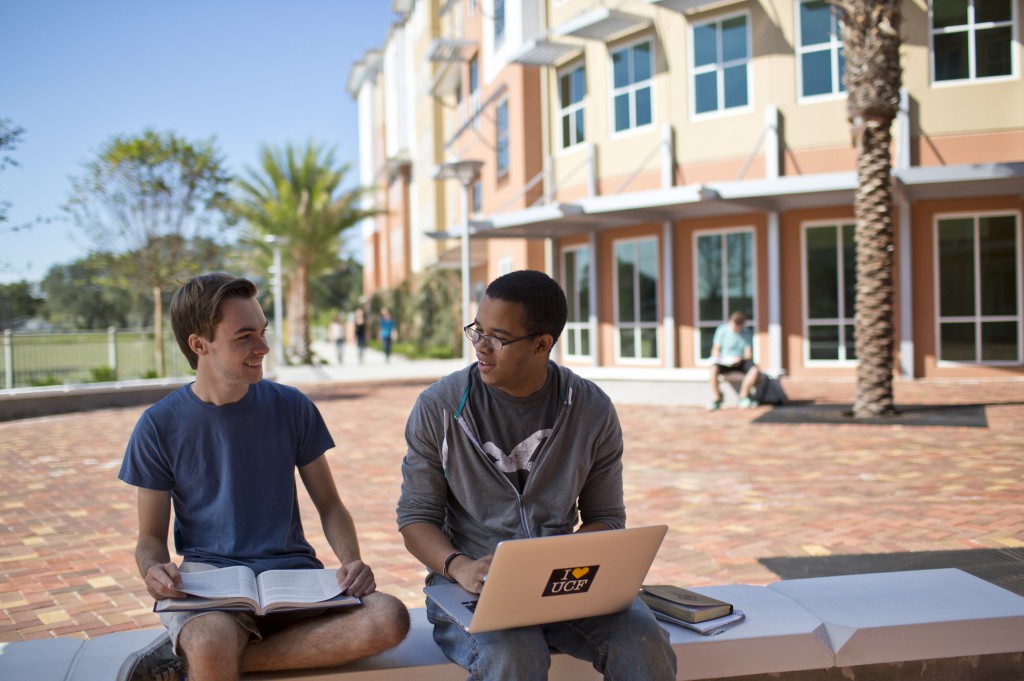 students sitting outside using laptop
