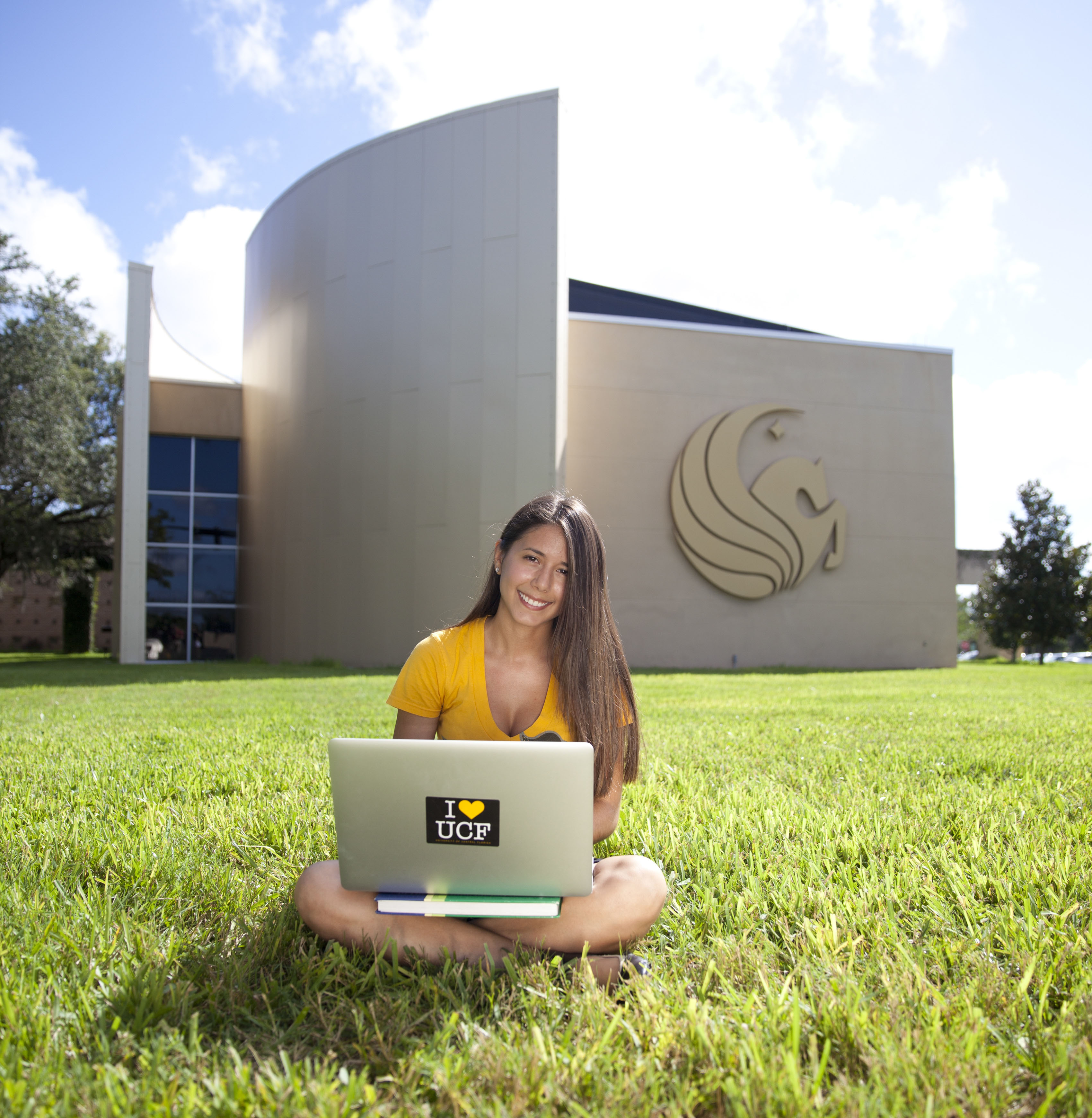 Student using computer in grass outside Welcome Center