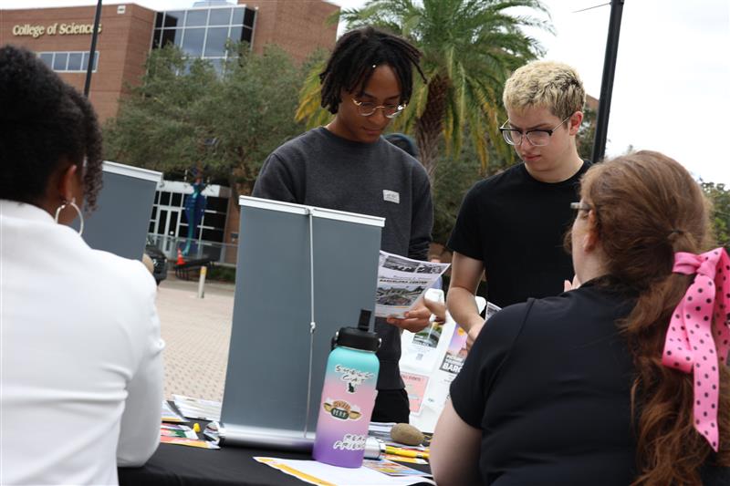 H10A1620 1 Students reviewing Study abroad materials at a UCF Abroad tabling event with two ladies at the table helping them